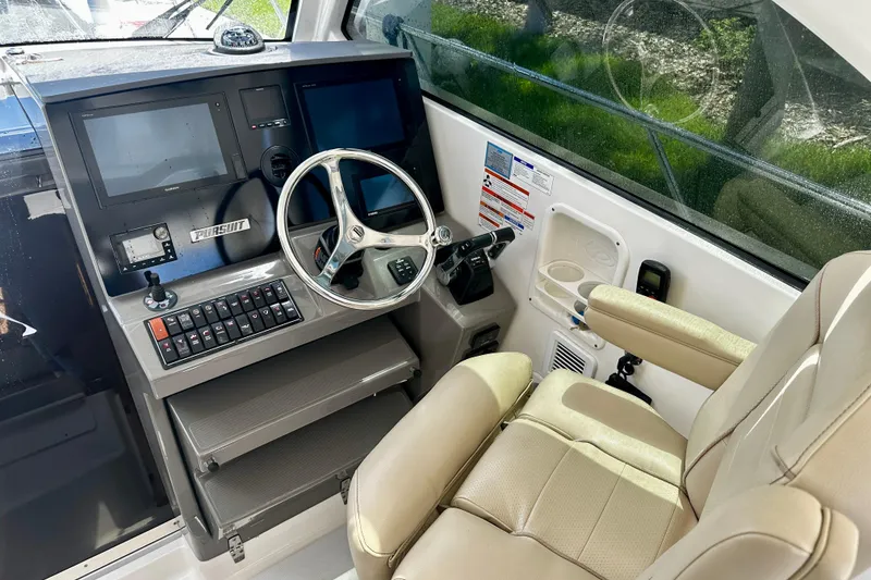 Slide: The Image of 2019 Pursuit OS 325 Offshore helm with dual screens, steering wheel, and comfortable seating. - 7