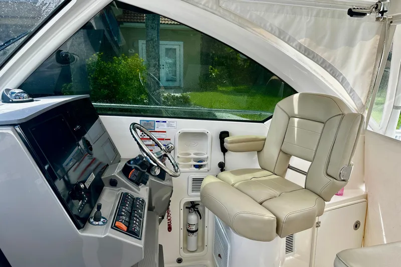 Slide: The Image of 2019 Pursuit OS 325 Offshore helm with beige captain's chair and modern controls. - 9