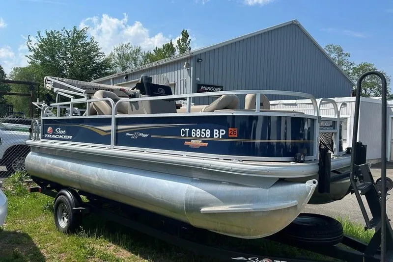 The Image of 2023 Sun Tracker Bass Buggy 18 DLX pontoon boat on trailer, parked outdoors. - 1