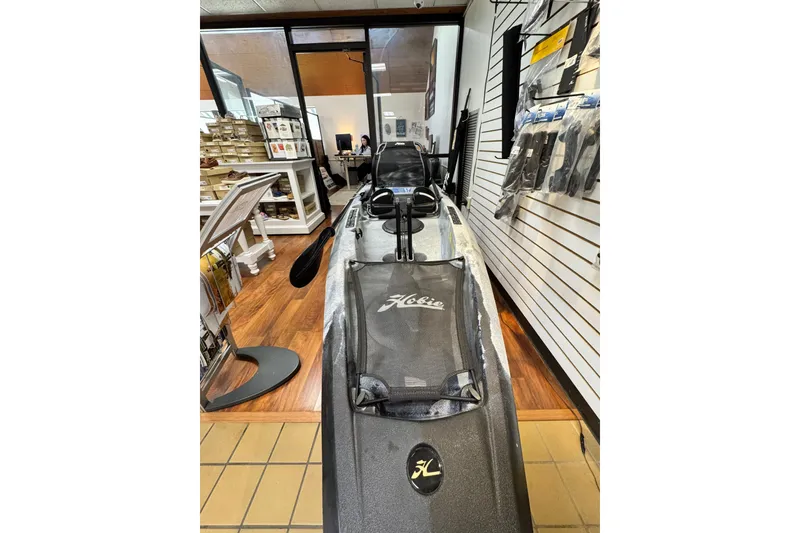 Slide: The Image of 2024 Hobie Mirage Compass kayak displayed in a store with accessories on shelves. - 2