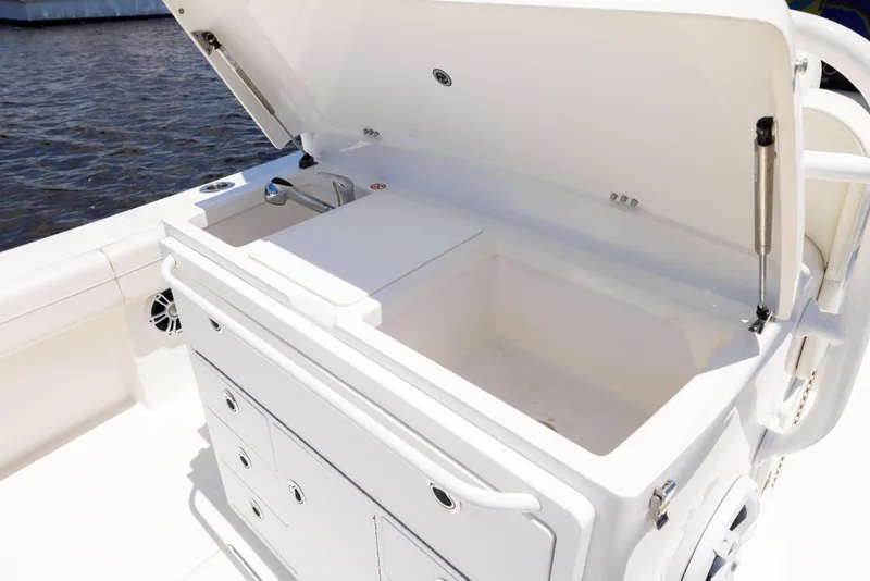 Slide: The Image of 2024 Regulator 34 boat with open storage compartment and sink, docked by the water. - 36