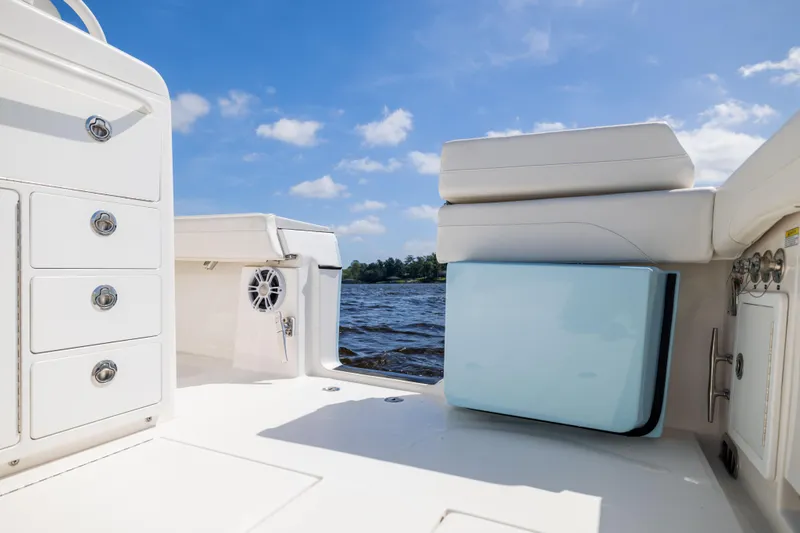 Slide: The Image of 2024 Regulator 34 boat interior with storage drawers and seating, under a clear blue sky. - 37