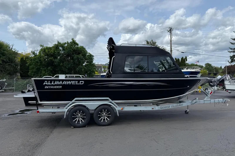 Slide: The Image of 2026 Alumaweld Intruder 22 HT boat on trailer, parked outdoors under cloudy sky. - 2