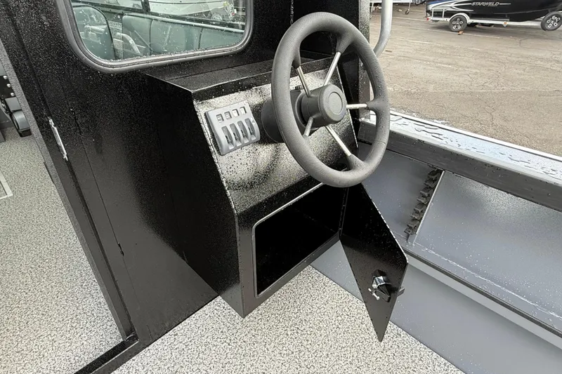 Slide: The Image of Steering console of 2026 Alumaweld Intruder 22 HT boat, featuring control panel and open storage compartment. - 25
