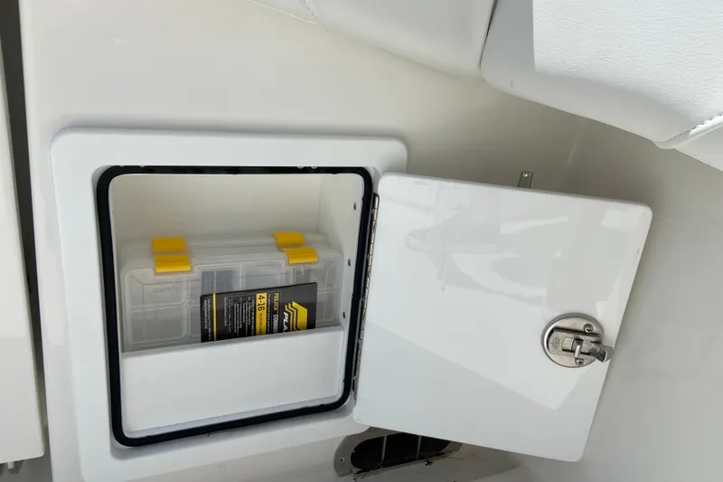 Slide: The Image of Storage compartment on a 2026 Regulator 31 boat, featuring a tackle box with yellow latches. - 7