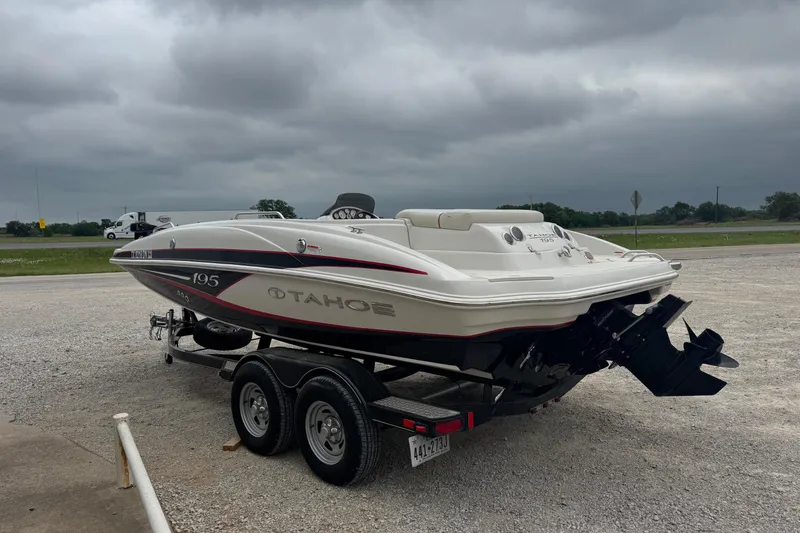 Slide: The Image of 2015 Tahoe 195 boat on trailer under cloudy sky, parked on gravel. - 5