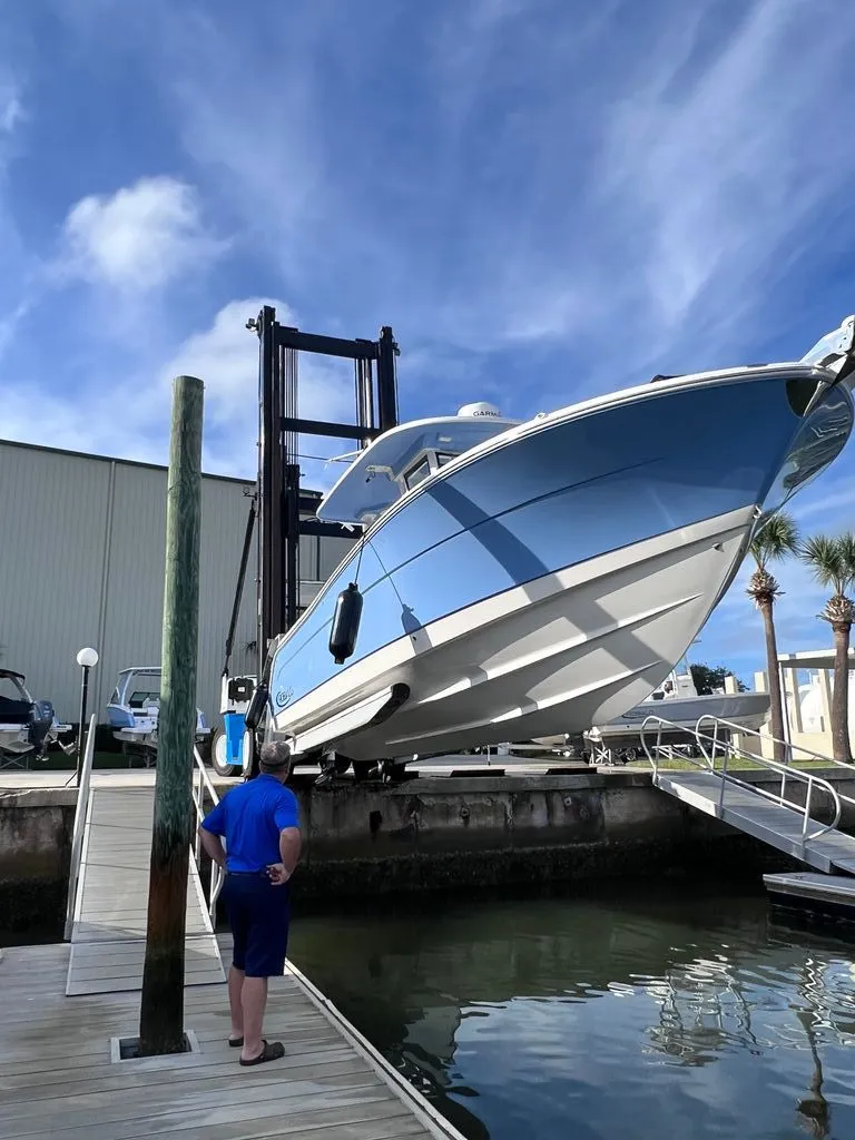 Slide: The Image of 2023 Robalo R302 Center Console on a boat lift at the dock. - 3