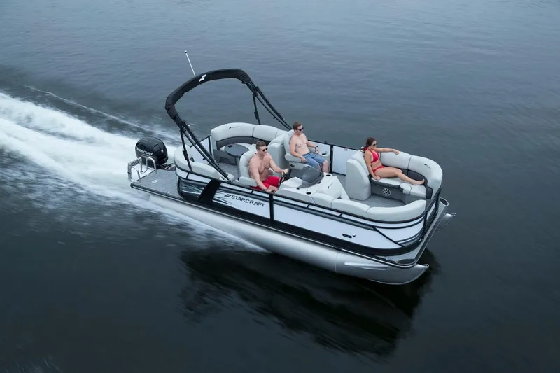 The Image of 2019 Starcraft SLS 1 pontoon boat on calm water with passengers. - 1