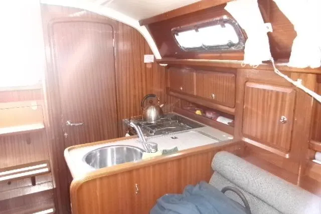 Slide: The Image of Interior of 2000 Bavaria Yachts sloop with wooden cabinetry and compact kitchen area. - 2