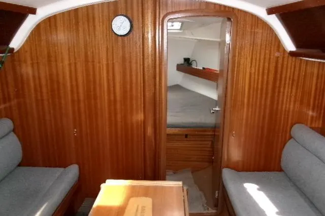 Slide: The Image of Interior of a 2000 Bavaria Yachts sloop, featuring wooden paneling and cozy seating. - 3