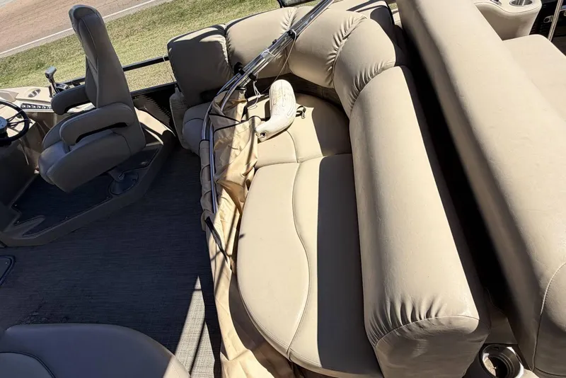 Slide: The Image of 2017 Manitou 25 SES BENCH boat interior with beige seating and steering area. - 2