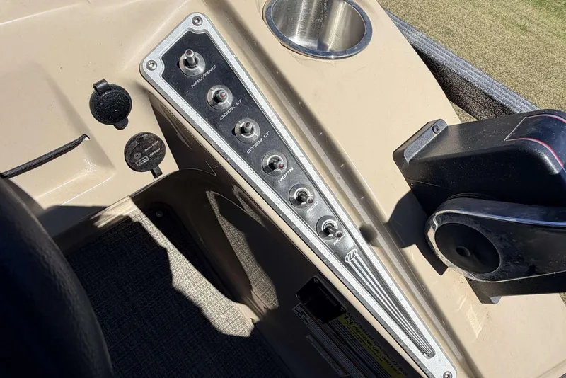 Slide: The Image of Control panel of a 2017 Manitou 25 SES BENCH boat with switches and cup holder. - 5