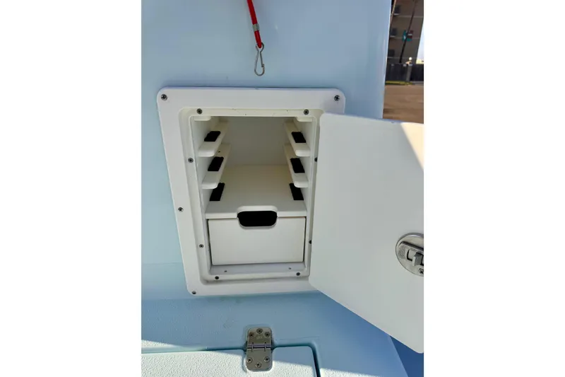 Slide: The Image of Open storage compartment on Waterman Wildwater 23 boat, showcasing interior shelves and latch. - 18
