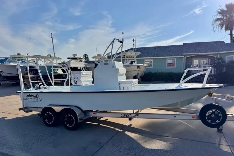 Slide: The Image of 2023 Waterman Wildwater 23 boat on trailer, parked outdoors under clear sky. - 2