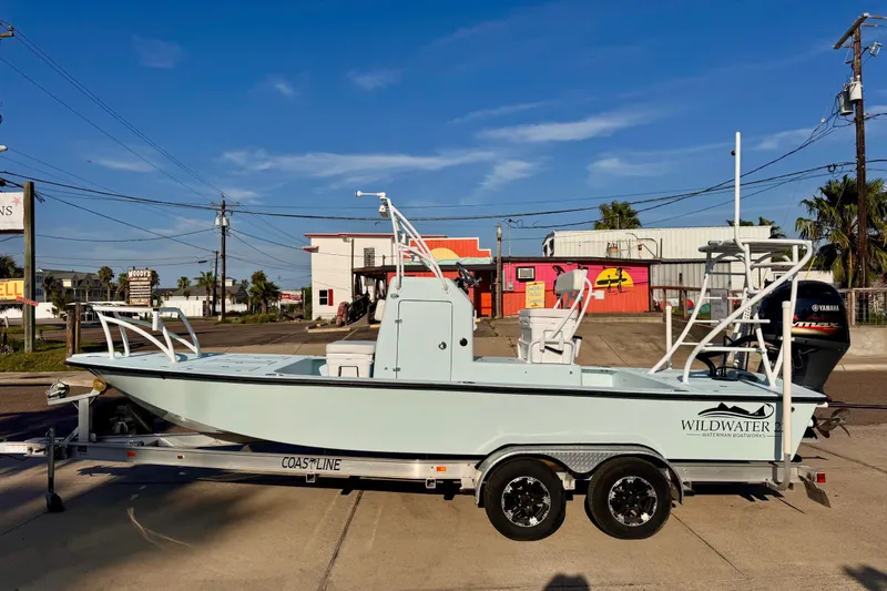 Slide: The Image of 2023 Waterman Wildwater 23 boat on trailer, parked outdoors under clear blue sky. - 3