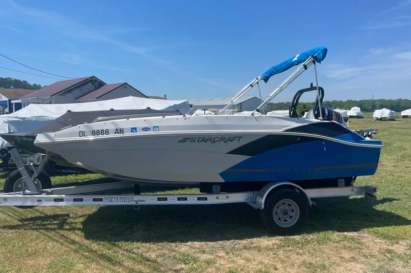 The Image of 2022 Starcraft SVX 171 OB boat on trailer, parked outdoors under clear blue sky. - 0