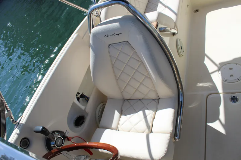 Slide: The Image of 2022 Chris-Craft Launch 27 boat interior with white quilted seat and wooden steering wheel. - 21