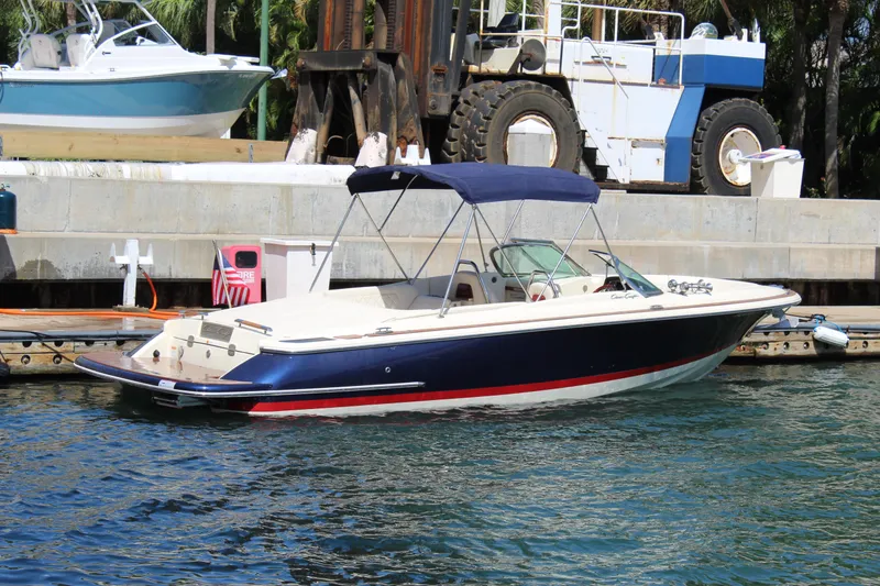 Slide: The Image of 2022 Chris-Craft Launch 27 boat docked in marina, featuring sleek design and blue canopy. - 31