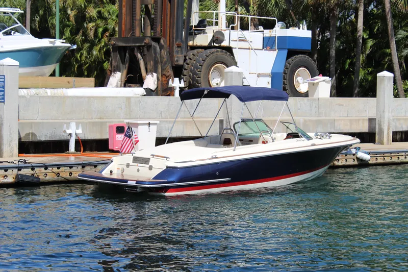 Slide: The Image of 2022 Chris-Craft Launch 27 boat docked in a marina, featuring a sleek design and canopy. - 32