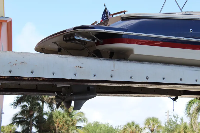 Slide: The Image of 2022 Chris-Craft Launch 27 boat on a lift, with palm trees in the background. - 35