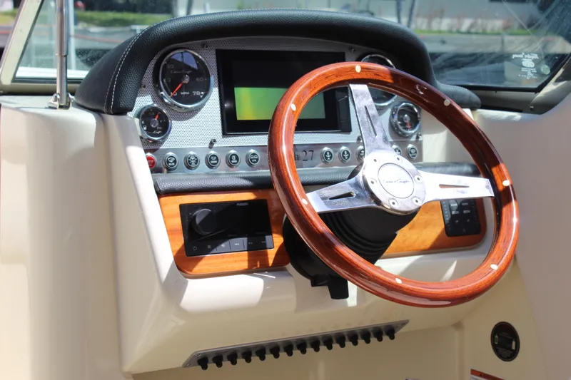 Slide: The Image of 2022 Chris-Craft Launch 27 dashboard with wooden steering wheel and modern controls. - 6