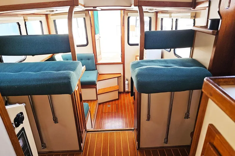 Slide: The Image of Interior of a 1996 Nordic Tug 26 boat with wooden flooring and teal seating. - 10