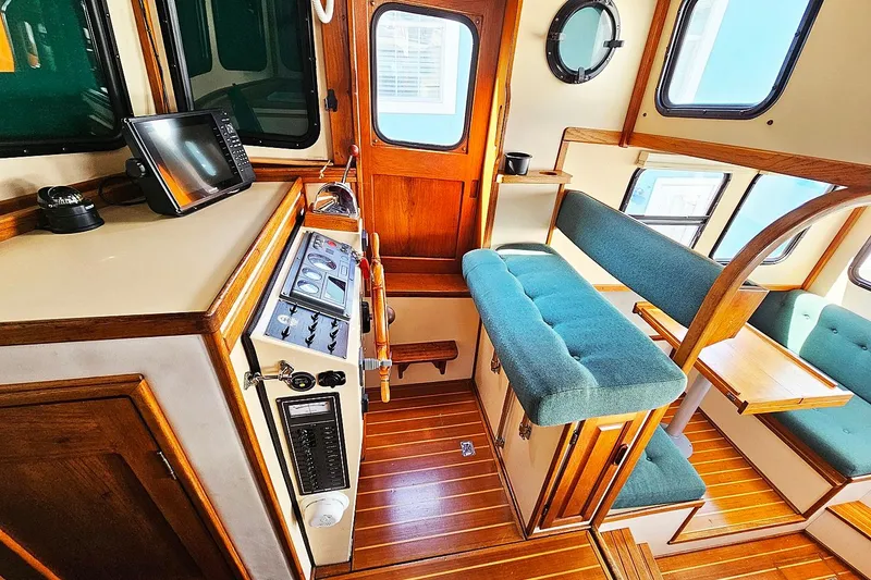 Slide: The Image of Interior of a 1996 Nordic Tug 26, featuring wood accents and teal seating. - 11