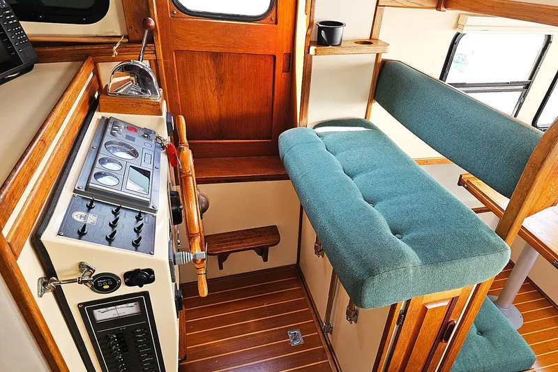 Slide: The Image of 1996 Nordic Tug 26 interior with helm, wooden accents, and teal seating. - 12
