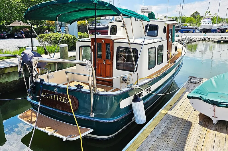Slide: The Image of 1996 Nordic Tug 26 docked at marina, featuring green canopy and wooden accents. - 19