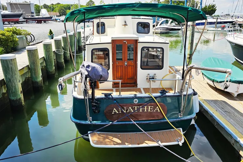 Slide: The Image of 1996 Nordic Tug 26 docked at marina, featuring green canopy and wooden accents. - 20