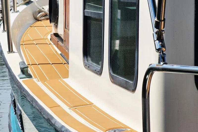 Slide: The Image of 1996 Nordic Tug 26 boat deck with windows and railing, docked on calm water. - 3