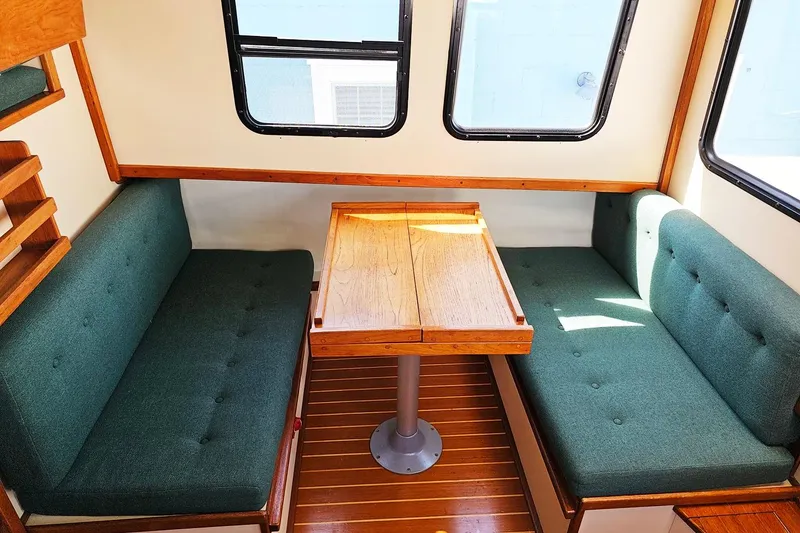 Slide: The Image of Interior of a 1996 Nordic Tug 26 with green cushioned seating and wooden table. - 5