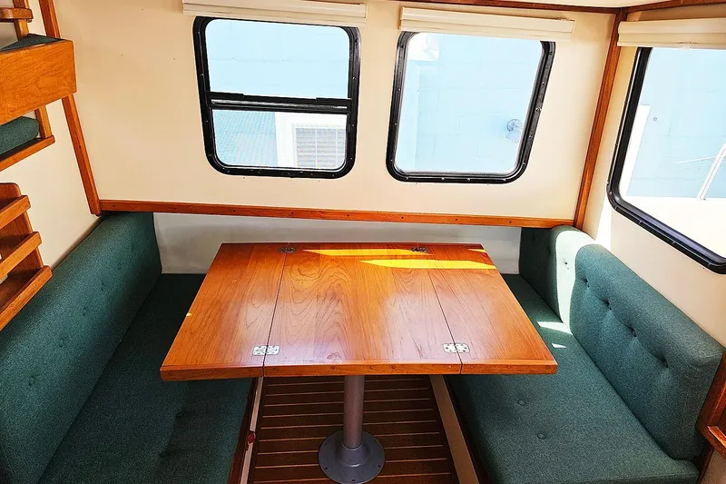 Slide: The Image of Interior of a 1996 Nordic Tug 26 with a wooden dining table and green seating. - 6