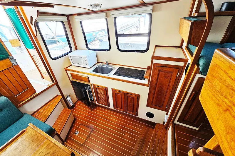 Slide: The Image of Interior of a 1996 Nordic Tug 26, featuring a compact kitchen with wooden cabinetry. - 7