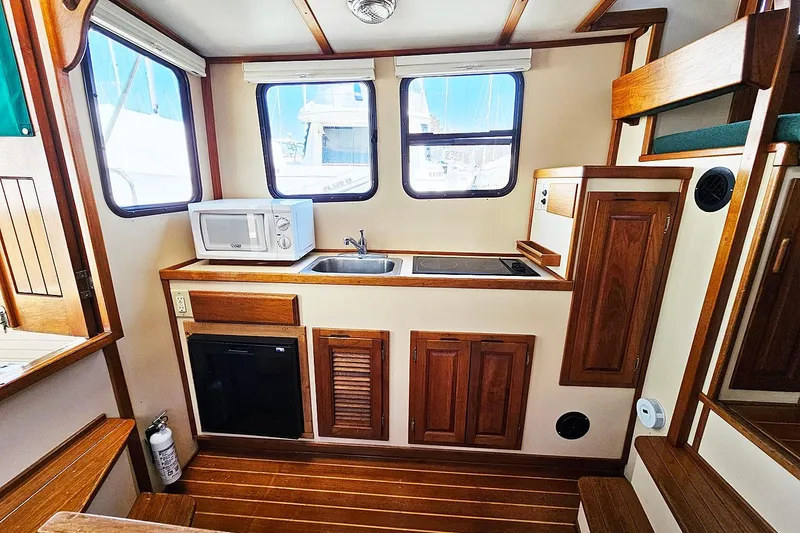 Slide: The Image of Interior of a 1996 Nordic Tug 26 with kitchenette, featuring wood cabinetry and modern appliances. - 8