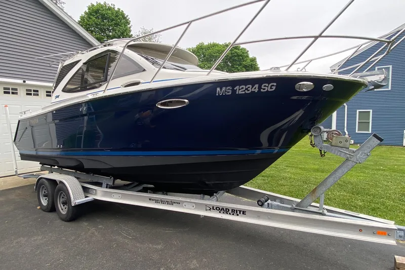 Slide: The Image of 2016 Cutwater C-24 boat on trailer, parked in driveway near house. - 2