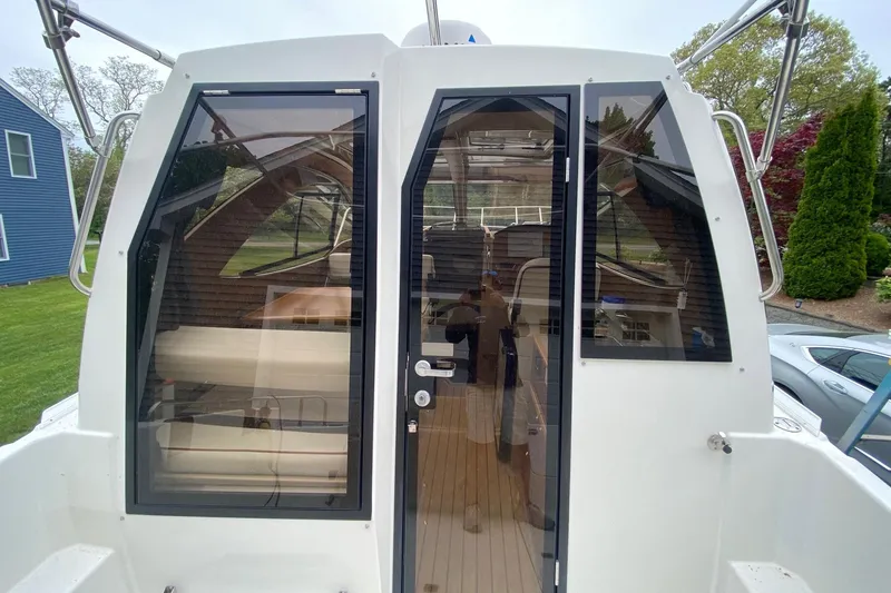 Slide: The Image of 2016 Cutwater C-24 boat with glass doors and windows, docked near a house. - 28