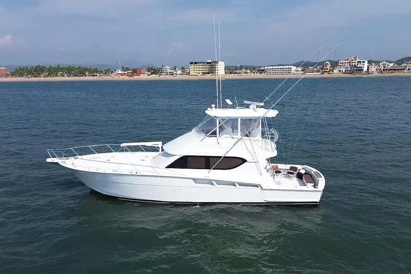 The Image of 2001 Hatteras 55 Convertible yacht on calm water near a coastal city. - 0