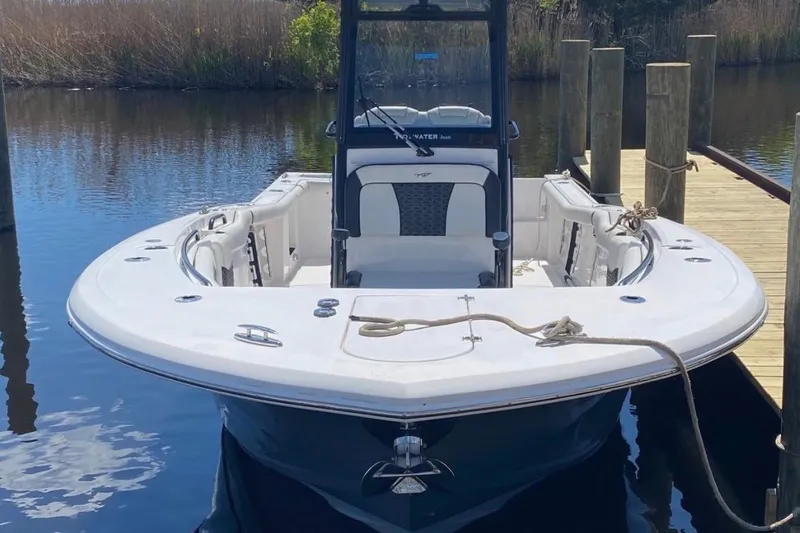 Slide: The Image of 2024 Tidewater 256 CC Adventure boat docked on calm water. - 2