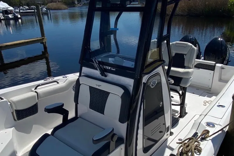 Slide: The Image of 2024 Tidewater 256 CC Adventure boat interior with seating and console, docked by the water. - 3