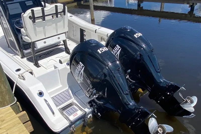 Slide: The Image of 2024 Tidewater 256 CC Adventure boat with dual Yamaha 150 engines docked by water. - 6