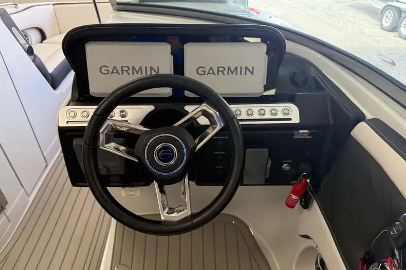 Slide: The Image of 2025 Crownline Eclipse E235 boat dashboard with Garmin displays and steering wheel. - 19