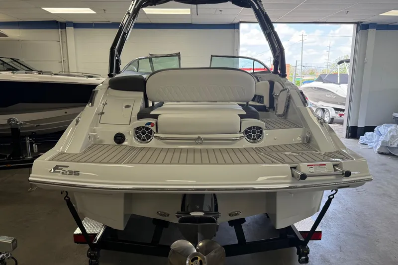 Slide: The Image of 2025 Crownline Eclipse E235 boat in showroom, rear view with seating and speakers. - 2