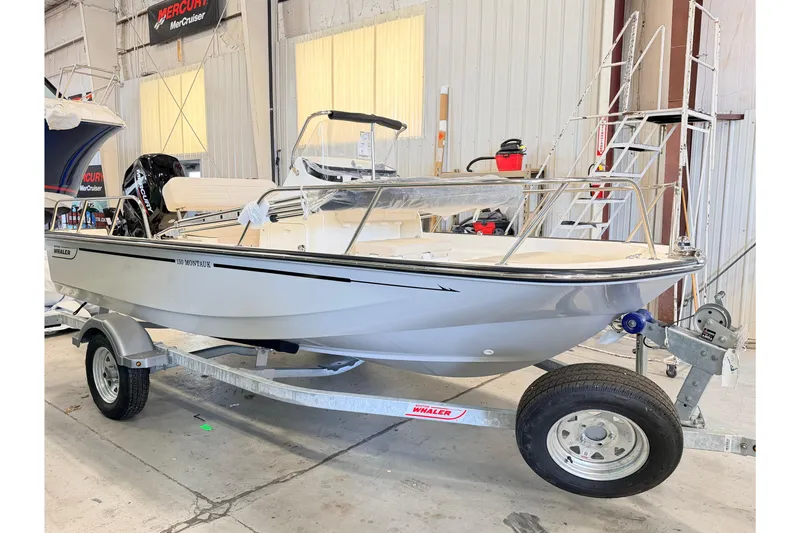 Slide: The Image of 2026 Boston Whaler 150 Montauk boat on trailer in indoor showroom. - 0