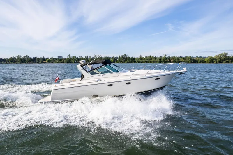 The Image of 1998 Tiara Yachts 3500 Express cruising on a sunny day, creating waves. - 1