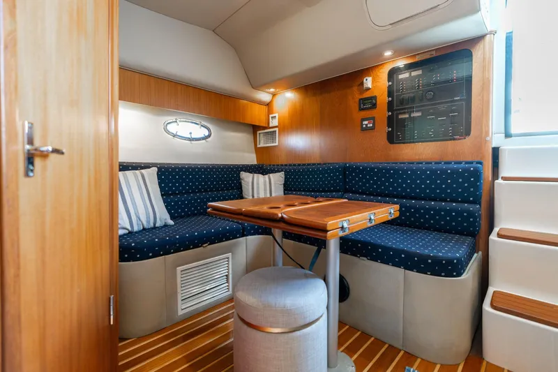 Slide: The Image of 1998 Tiara Yachts 3500 Express interior with blue seating, wooden table, and control panel. - 12