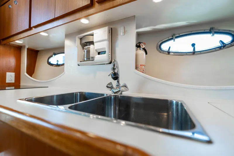 Slide: The Image of 1998 Tiara Yachts 3500 Express kitchen with stainless steel sink and porthole windows. - 14