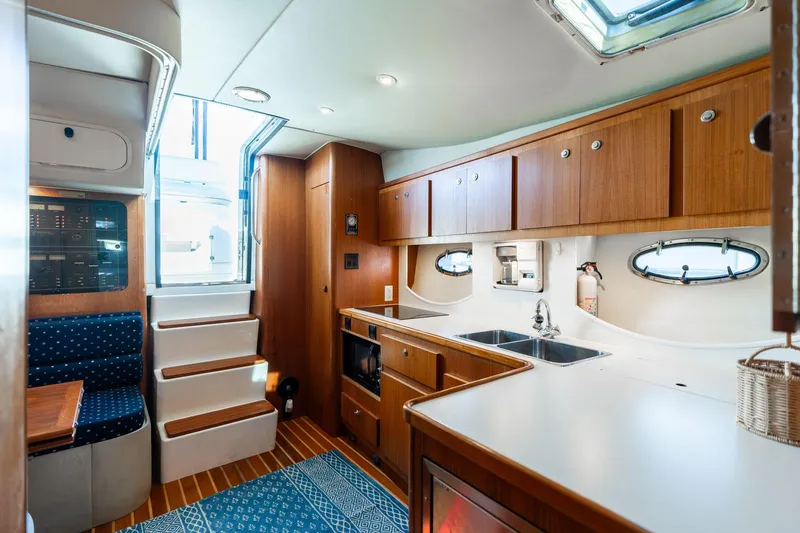 Slide: The Image of Interior of a 1998 Tiara Yachts 3500 Express, featuring a cozy kitchen and seating area. - 15