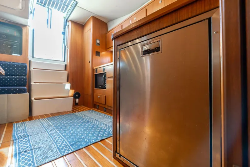 Slide: The Image of Interior of 1998 Tiara Yachts 3500 Express, featuring wood cabinetry and stainless steel appliances. - 16