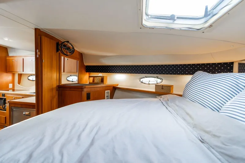 Slide: The Image of 1998 Tiara Yachts 3500 Express cabin interior with bed, wood finish, and porthole windows. - 20